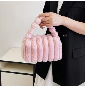 Fashionable pink plush handbag with ribbed texture and beaded handle held by a model