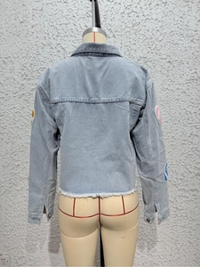 Rear view of a light blue cropped denim jacket featuring a frayed fringe hem and long sleeves