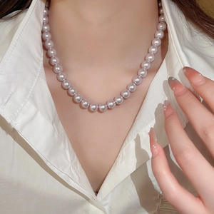 Detailed view of lavender pearl necklace worn by a model on a white shirt