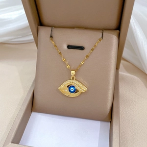 Detailed close-up of Evil Eye pendant with blue stone in a beige jewelry box