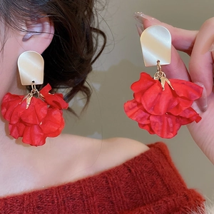 Detailed view of oversized red fabric flower tassel earrings with matte gold metal accents