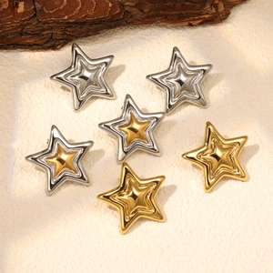 Three-layer star earrings in gold and silver finishes on a natural bark textured background