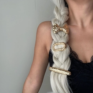 Three-piece gold hammered metal hair clip set with bow and geometric shapes on braided hair