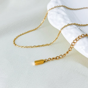 Detail of 14K gold-plated stainless steel fine chain necklace on a ceramic plate