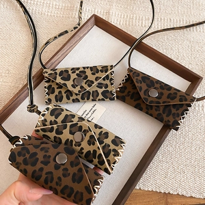 Detail of leopard print leather mini bag pendants with white stitching and metal snaps