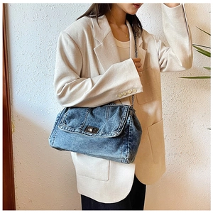 Retro denim tote bag with metal chain strap worn by a model in a beige blazer
