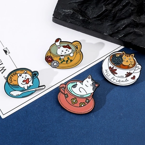Detailed view of four colorful enamel coffee cup cat pins on a dark textured background