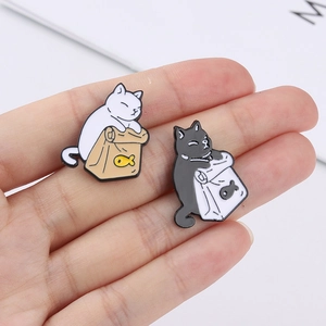 Cute black and white enamel cat pins on brown and white paper bags, fashion badges