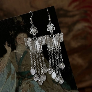 Detail of silver hollow butterfly tassel earrings on a vintage oriental background