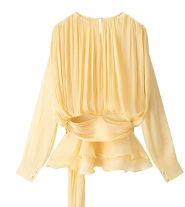 Detailed view of light yellow long-sleeve ruffled top with delicate pleated fabric textures