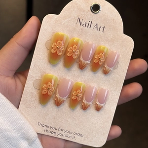 Detail of almond nails with orange gradient, 3D relief flowers, and gold bead accents