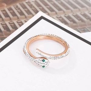 Macro view of rose gold snake ring featuring white crystals and green gemstone eyes