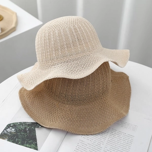 Detail of elegant wavy-brimmed straw hats in beige and light brown with woven textures