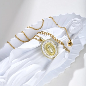 Gold Virgin Mary oval pendant necklace with zircon stones on a white sculpture