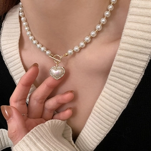 Elegant pearl necklace with diamond-encrusted heart pendant and gold toggle clasp