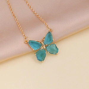 Macro detail of golden butterfly necklace with blue zircon pendant on silk background