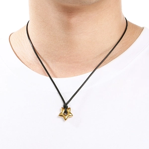 Close-up of a gold star pendant on a black braided cord necklace worn by a model