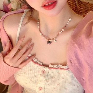 Close-up of beaded necklace with pearls, heart charms, and a dark floral pendant on a model