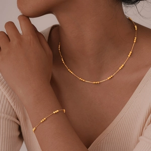 Elegant gold beaded necklace and bracelet jewelry set for women worn by a model