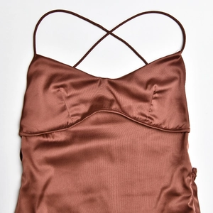 Détail d'une robe en satin marron avec fines bretelles croisées et texture soyeuse
