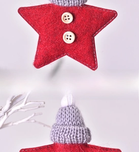 Detail of red felt star ornament with knitted mini hat and decorative white stitching