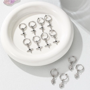Titanium steel hoop earrings with starburst and cross charms in a silver-toned finish