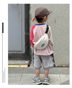 Rear view of a white canvas kids chest bag with blue logo and adjustable strap