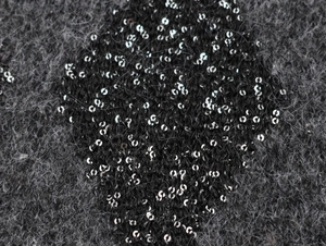 Macro detail of dark grey knit fabric with shimmering black sequins for women top