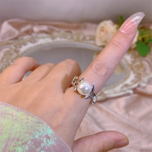 Detail of elegant silver twig ring with large white pearl on pink silk background