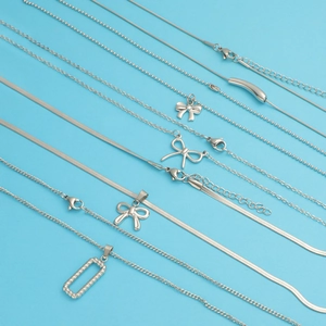Silver titanium steel necklaces set with bow, square and pipe pendants on blue background