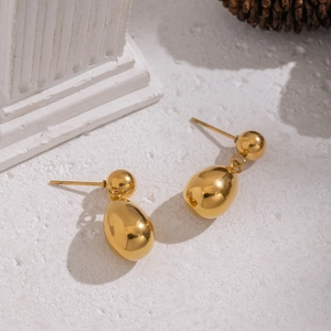 Minimalist gold droplet earrings in polished stainless steel displayed on stone