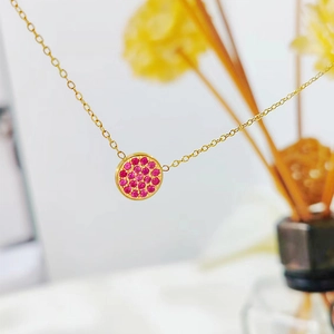 Macro shot of gold stainless steel necklace with round pendant set with pink crystals