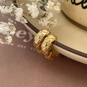 Close-up of golden quilted pattern earrings on a ceramic dish edge with elegant decor