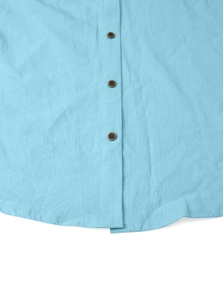 Close-up of brown vintage buttons and breathable linen fabric on light blue shirt hem
