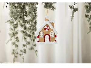 Detailed view of gingerbread house ornament with snowy white roof on Christmas tree