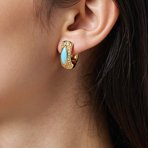 Detailaufnahme der 18K vergoldeten Creolen mit blauem Stein am Ohr des Models