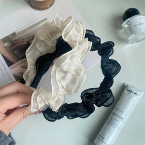 Detailed view of beige and black ruffled mesh headbands with pleated tulle texture