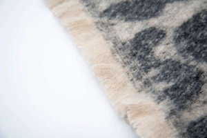 Close-up of leopard print scarf with soft gray jacquard texture and fringed edges