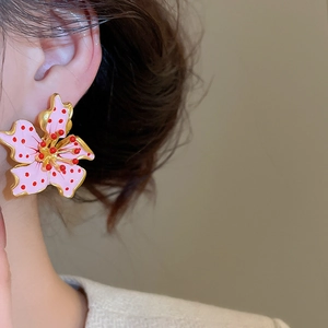Close-up of elegant flower stud earrings with pink enamel and red polka dots for women