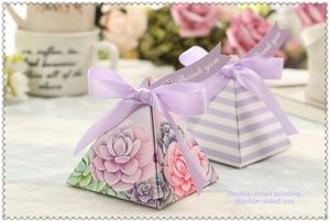 Close-up of pyramid candy boxes with floral patterns, purple ribbons, and Thank You tags