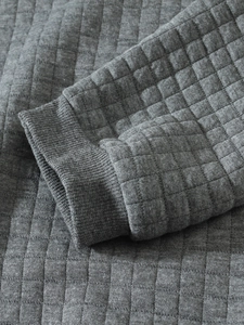 Close-up of dark grey quilted fabric texture and ribbed cuffs on men's sweatshirt