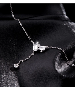 Macro view of emerald-cut and round-cut stones on Y-necklace against black leather