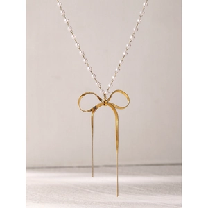 Detail of 18k gold plated bow pendant with long tassels and elegant pearl bead chain
