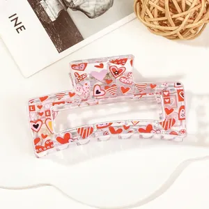 Detail view of transparent rectangular hair claw with red love heart and stripe patterns