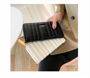 Pochette lunghe in pelle trapuntata in nero e beige tenute da una modella con stile