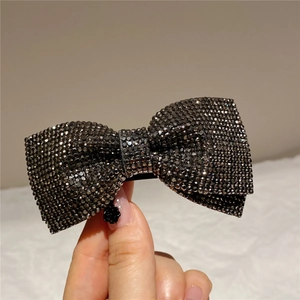 Macro view of a handmade bow hair clip embellished with shimmering dark grey rhinestones