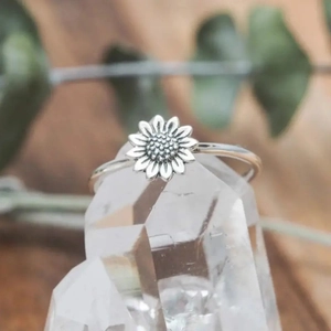 Macro view of silver sunflower ring with intricate petal detail on crystal display