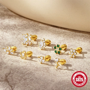 S925 sterling silver gold earrings set with white and green zircons on stone background