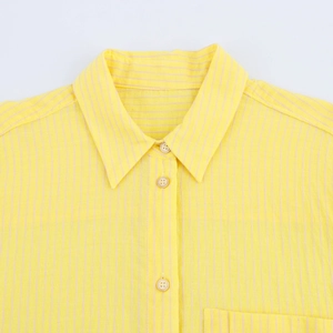 Dettaglio del colletto della camicia a righe gialle con bottoni beige e trama in cotone