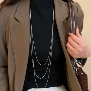 Close-up of minimalist layered silver tassel necklace on a model with a dark turtleneck